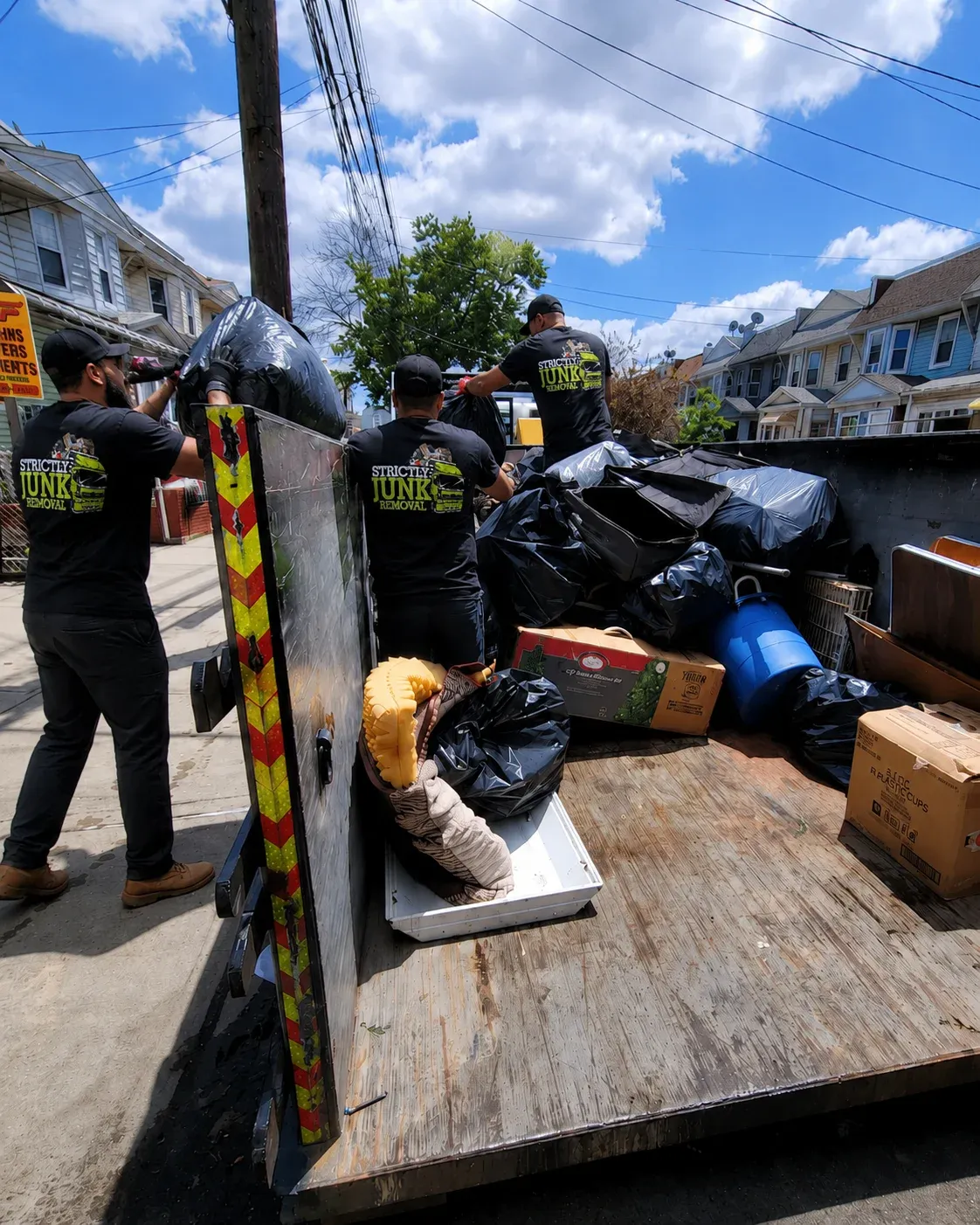 Strictly Junk Removal crew loading furniture into the truck on a Brooklyn street
